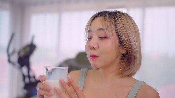 幸福的亚洲女人在健身房喝牛奶的画像