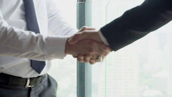 高级商人在办公室会见后一同握手祝贺与约定商业伙伴握手合并与合作为成功协议的业务