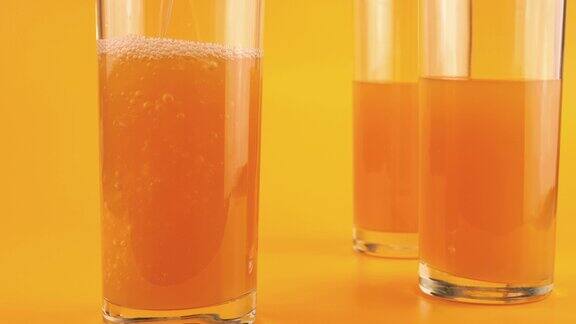 苹果汁被倒入橘色背景的高脚杯中缓慢的运动
