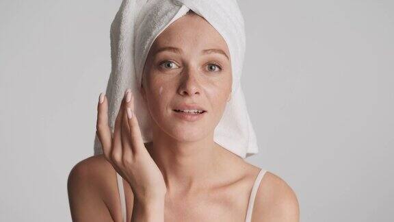 美丽的女孩用毛巾在头上涂抹保湿霜