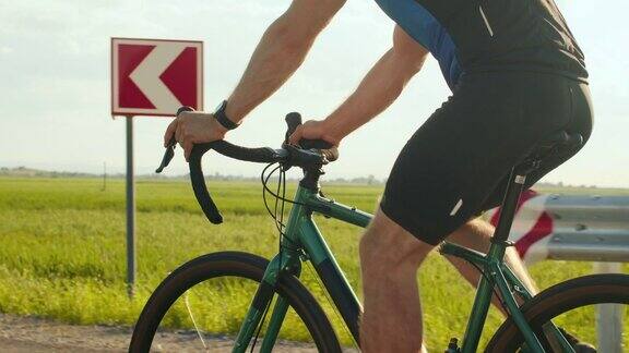 一个骑自行车的运动员正沿着公路骑车自行车手的腿的特写骑自行车训练4k