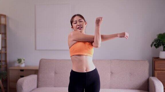 年轻漂亮身材匀称年轻运动的亚洲女士穿着运动服在家里的健身垫上进行热身伸展运动