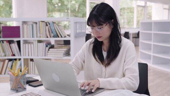 年轻的亚洲女大学生们正在用笔记本电脑认真地完成作业在网上提交作业参加网上课程或在大学图书馆准备考试