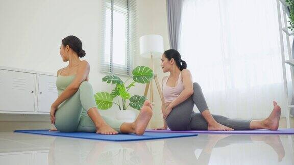 亚洲活跃的运动女性学习瑜伽普拉提课教练教练迷人的年轻女孩穿着运动服在客厅用垫子锻炼在家里跟随健身教练锻炼健康