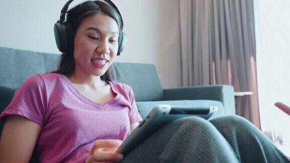 女人一边听音乐一边使用数码平板电脑在家休息