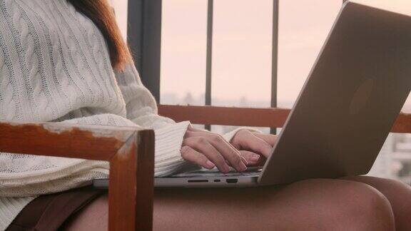 年轻的亚洲女商人穿着休闲服装在日落时分用笔记本电脑工作