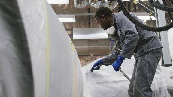 非裔美国男性汽车修理工正在用软管清洗汽车