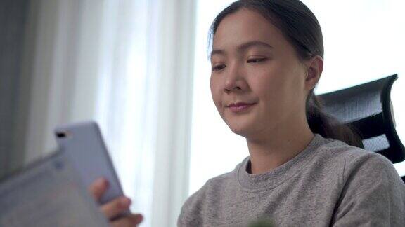 亚洲女性使用智能手机扫描二维码在家里办公室网上支付电费