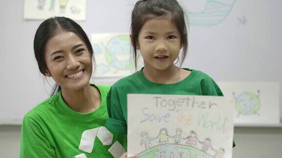 身穿绿色生态t恤的小女孩和老师的画像手里拿着拯救世界计划的画纸志愿、自然、教育理念