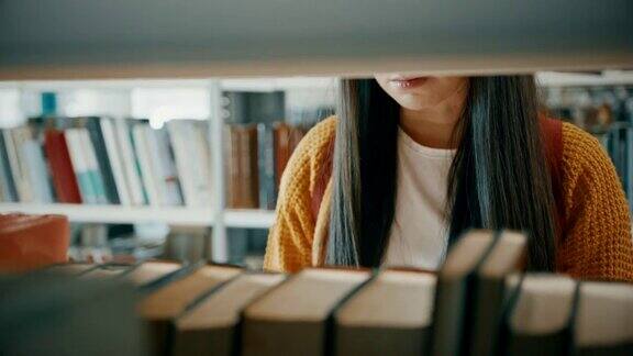 女学生在图书馆的书架上寻找一本书