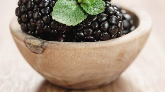 特写:木桌上的小木碗里盛着一锅黑莓