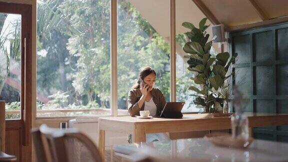 亚洲女商人在咖啡店用手机工作