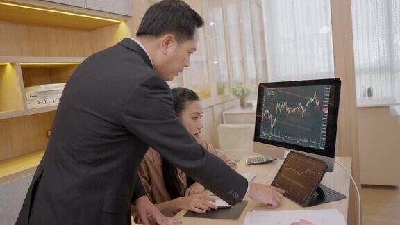 图为亚洲证券经纪人们正在办公室里用股票市场趋势显示器进行对话商务人士在办公室用平板电脑和电脑一起分析和头脑风暴股市交易图与金融合作的想法