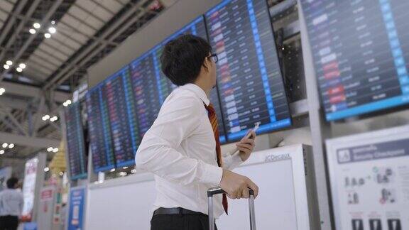 在国外出差期间在素万那普机场一名男职员正在检查登机牌并查看到达和离开登机口的登机时间