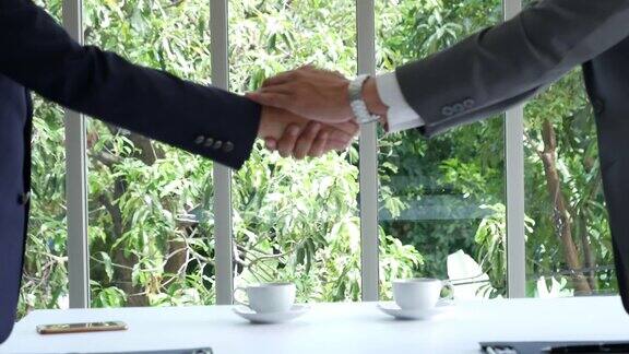 成功的合作伙伴签订合同并握手后成功的企业合资交易商人在会议上握手诚信的会议经营理念