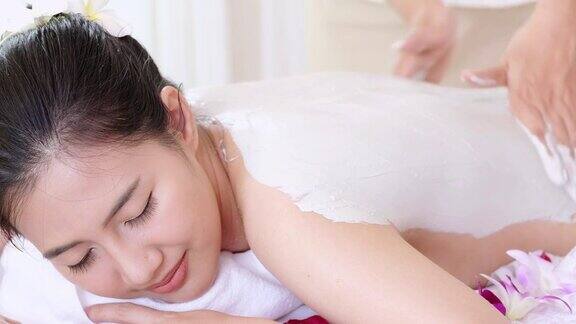 年轻女子躺在温泉床上按摩和粘土身体面膜放松