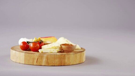 不同种类的奶酪西红柿和一碗果酱放在木板上