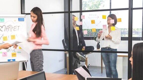 4K平移时间推移一群年轻的亚洲人或业务同事同事一起在现代办公室工作创意团队头脑风暴会议商业伙伴的想法分享或团队概念