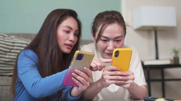 4K亚洲女性朋友一起在客厅用智能手机玩游戏