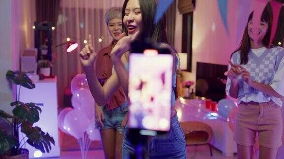 抖音的年轻亚洲女性朋友们用智能手机制作了她的舞蹈视频晚上在多彩的家庭派对上玩得很开心