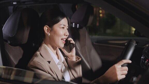 女人在晚上开车穿过城市回家时用手机