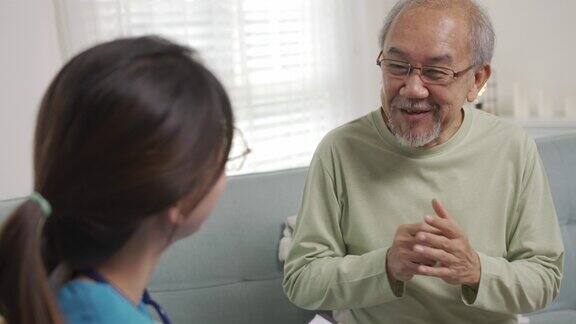 亚洲护理人员在家中客厅与年长男性病人交谈年长的老人在理疗后咨询护士辅助救援