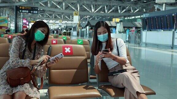 两名年轻的亚洲女性在机场使用智能手机
