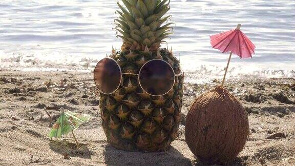 菠萝配太阳镜和椰子配伞是沙滩上的日光浴