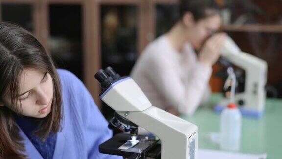 女学生在课桌上使用显微镜