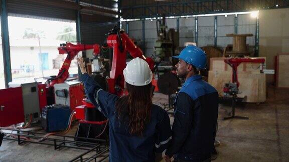 该公司的女工程师和男技术操作人员制造机器人检查工业机器人手臂的性能