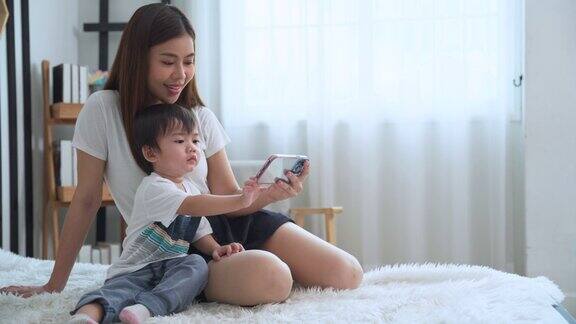 妈妈用智能手机打开社交媒体促进她可爱的小儿子发育