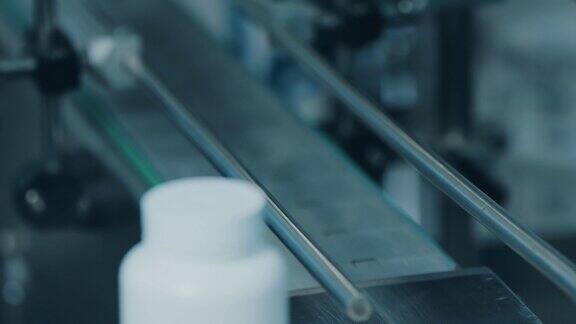 把瓶盖放在白色塑料管上的过程工厂里的管子沿着传送带移动很多白色的塑料瓶制药行业特写微距