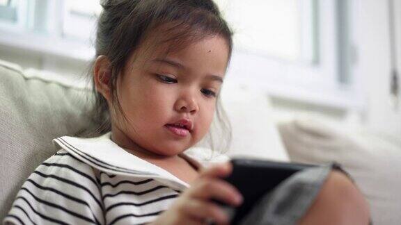 一个女孩坐在沙发上用智能手机玩手机游戏在客厅