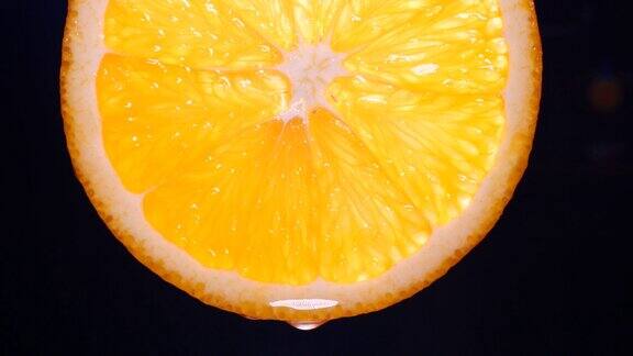 将一个橙色的水果切成薄片在果皮上加水并以黑色为底