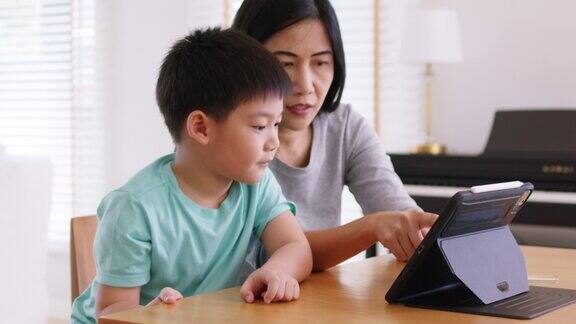 孩子和妈妈享受周末活动一起在家玩在线游戏