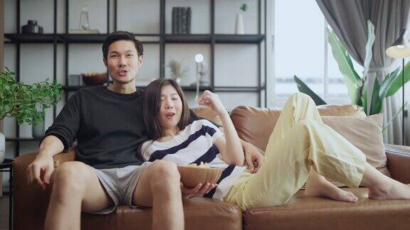 亚洲成人恋人结婚夫妇享受在沙发沙发上看电视一起在家里享受宁静和幸福居家隔离的生活方式