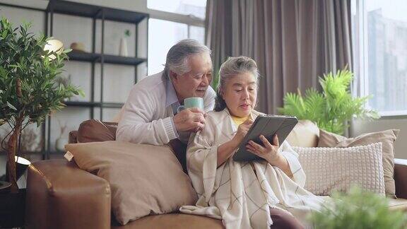 亚洲老年退休夫妇在沙发上与家人一起享受视频通话幸福地笑着笑着快乐地呆在家里亚洲老年成熟成人居家隔离期概念