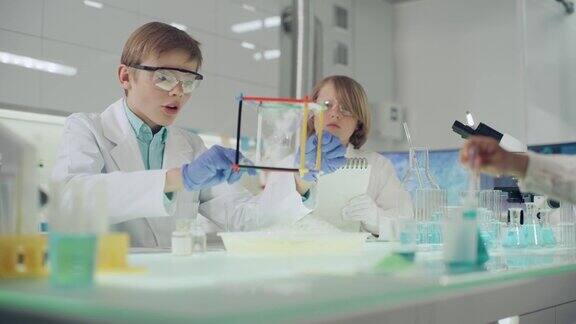 孩子们在实验室里做科学实验用肥皂泡液研究表面张力做笔记