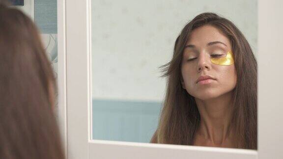 眼部皮肤护理肖像拍摄在一个迷人的年轻女子用黄金眼罩美丽的女孩使用胶原蛋白补丁