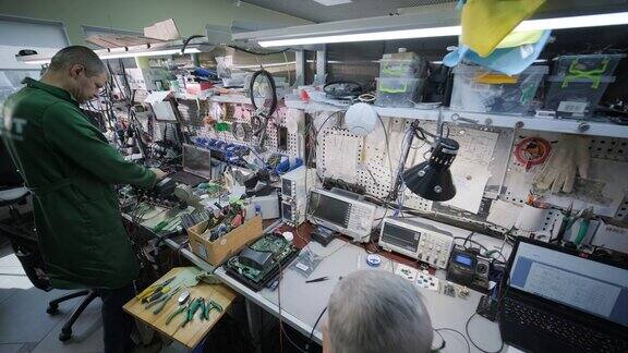 电子设备修理店工程师技术员在显微镜下焊接电子设备的印刷电路板