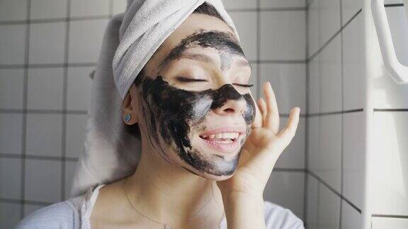 女性在面部涂抹黑色营养面膜