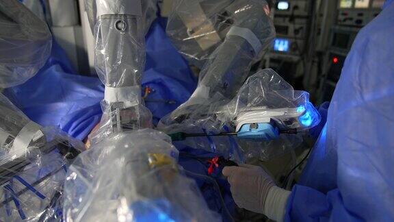 机器人外科医生给病人做手术设备臂在病人体内移动站在旁边的外科医生拿着器械靠近机械臂