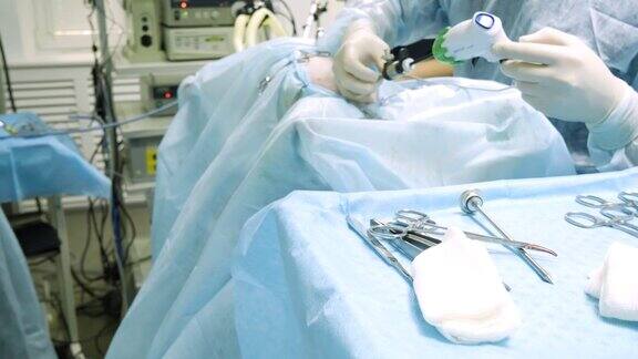 许多钢制手术器械放在无菌布上在医生身后外科医生为内窥镜手术设置端口内窥镜手术工具