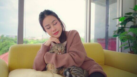 漂亮的亚洲女人和她的猫躺在沙发上