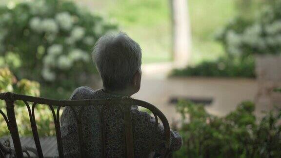 背后的老老人老年妇女坐在休息放松在天井看花园