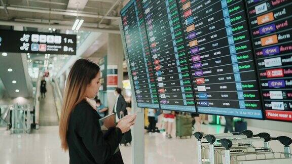 亚洲妇女查看机票和信息显示上的航班信息