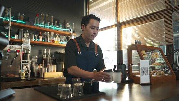 4K亚洲男子咖啡师在吧台为顾客准备外卖点的热咖啡