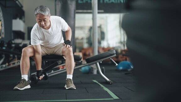 亚裔华人老人在健身房用哑铃锻炼