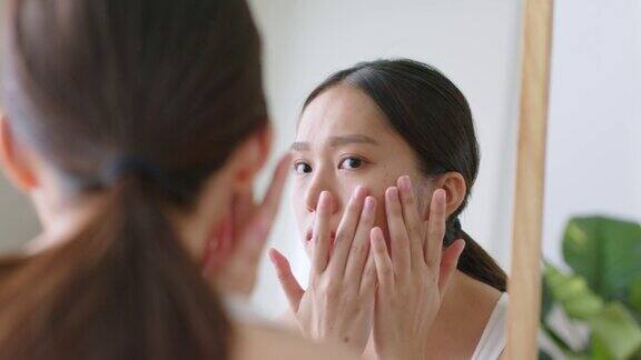 年轻的亚洲美女在镜子里检查她脸上的斑点和皮肤问题亚洲美容皮肤