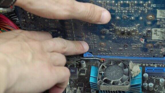 一个技术员的手拿出一个布满灰尘的显卡与主板在一个布满灰尘的旧电脑